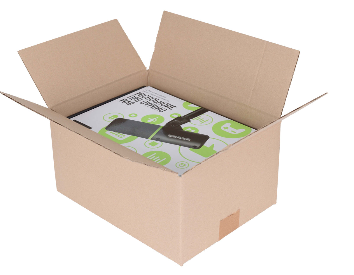 An open brown cardboard shipping box containing a boxed product with a black remote and green-and-white printed insert, shown on a plain white background.